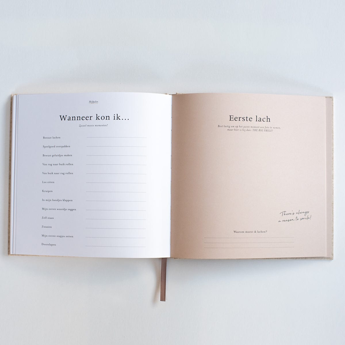 Invulboek Mijn Eerste Jaar, open bij de pagina’s ‘Wanneer kon ik…’ en ‘Eerste lach’, met ruimte om in te vullen.