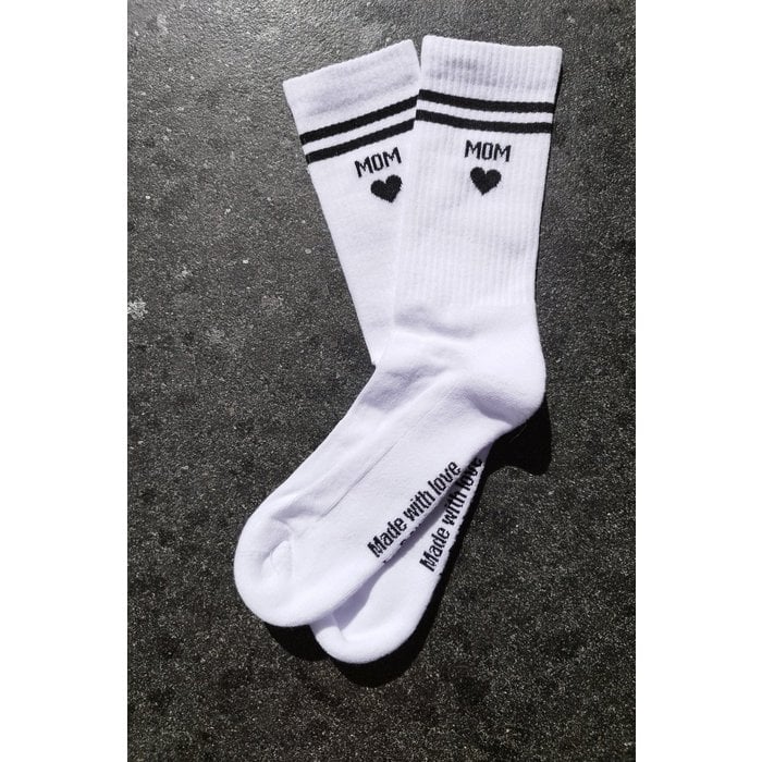 Witte Mom-sokken met zwarte strepen en hartjes op een donkere ondergrond, met ‘Made with love’ op de zool.