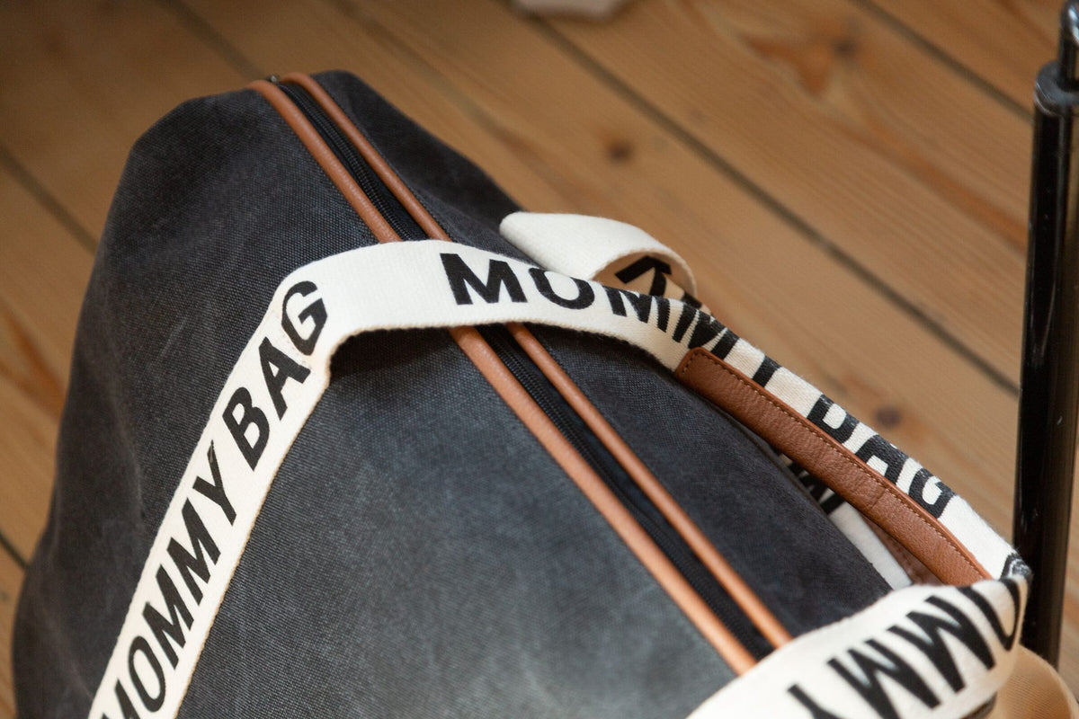 Bovenaanzicht van de zwarte Mommy Bag verzorgingstas met bruine ritsdetails en handgrepen met opdruk.