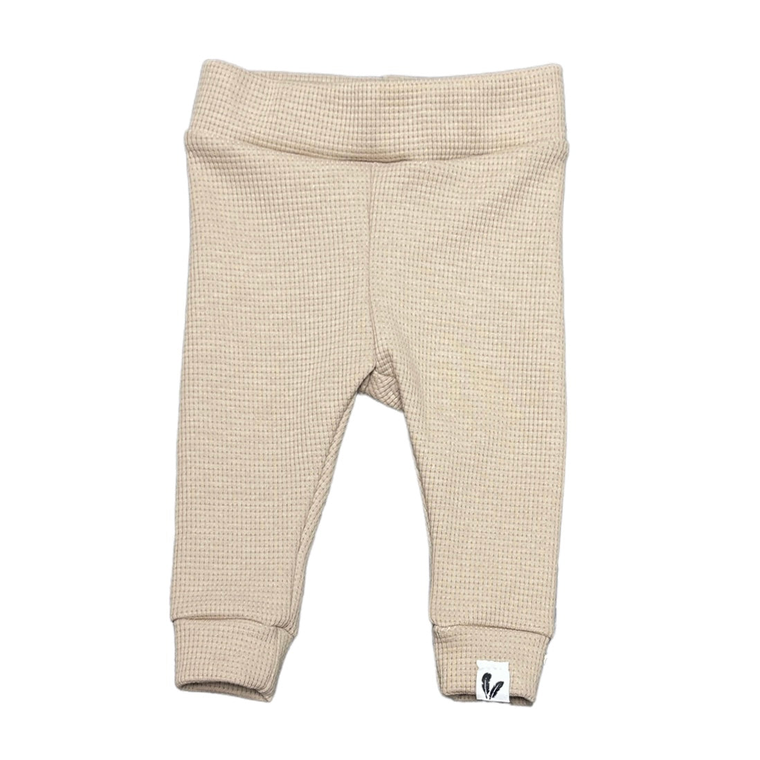 Beige newborn broekje met wafelstructuur, brede tailleband, boorden aan de pijpen en een klein label onderaan.