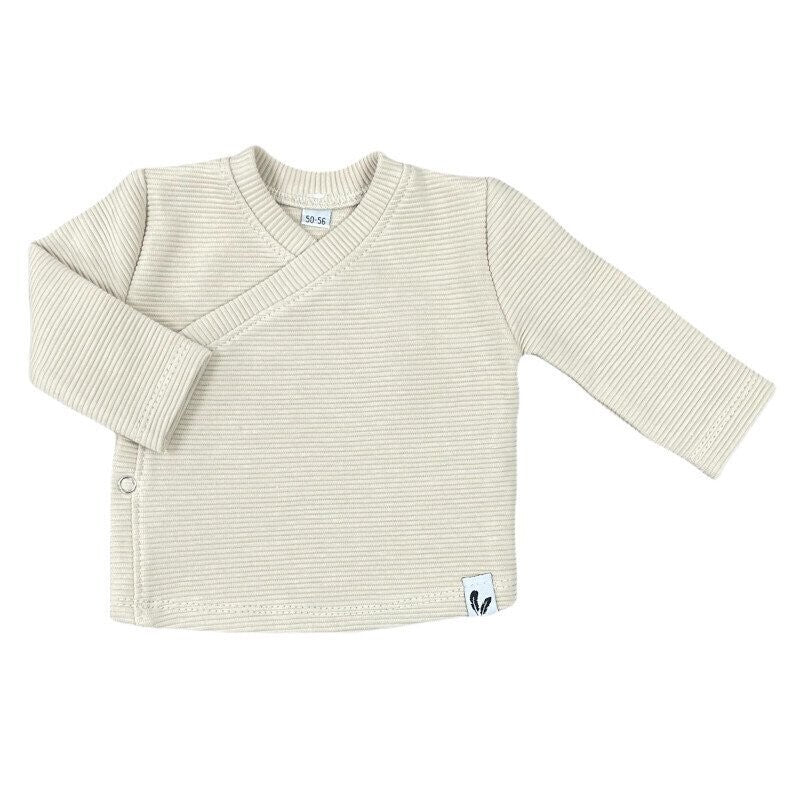 Beige overslagshirtje in ribstof met lange mouwen en een drukknoop aan de zijkant.