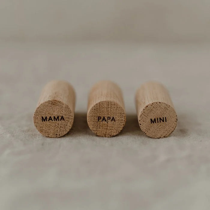 Drie eikenhouten Family-wandhaken naast elkaar, met de gegraveerde opschriften Mama, Papa en Mini.