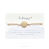 Armbandje Ik Draag Je met lichtroze koord en goudkleurige ronde vlinderbedel op een kaartje met gedicht.
