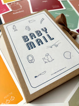 Baby Mail-mijlpaalkaarten in een bruin bewaardoosje met sluitlint, omringd door gekleurde kaarten.