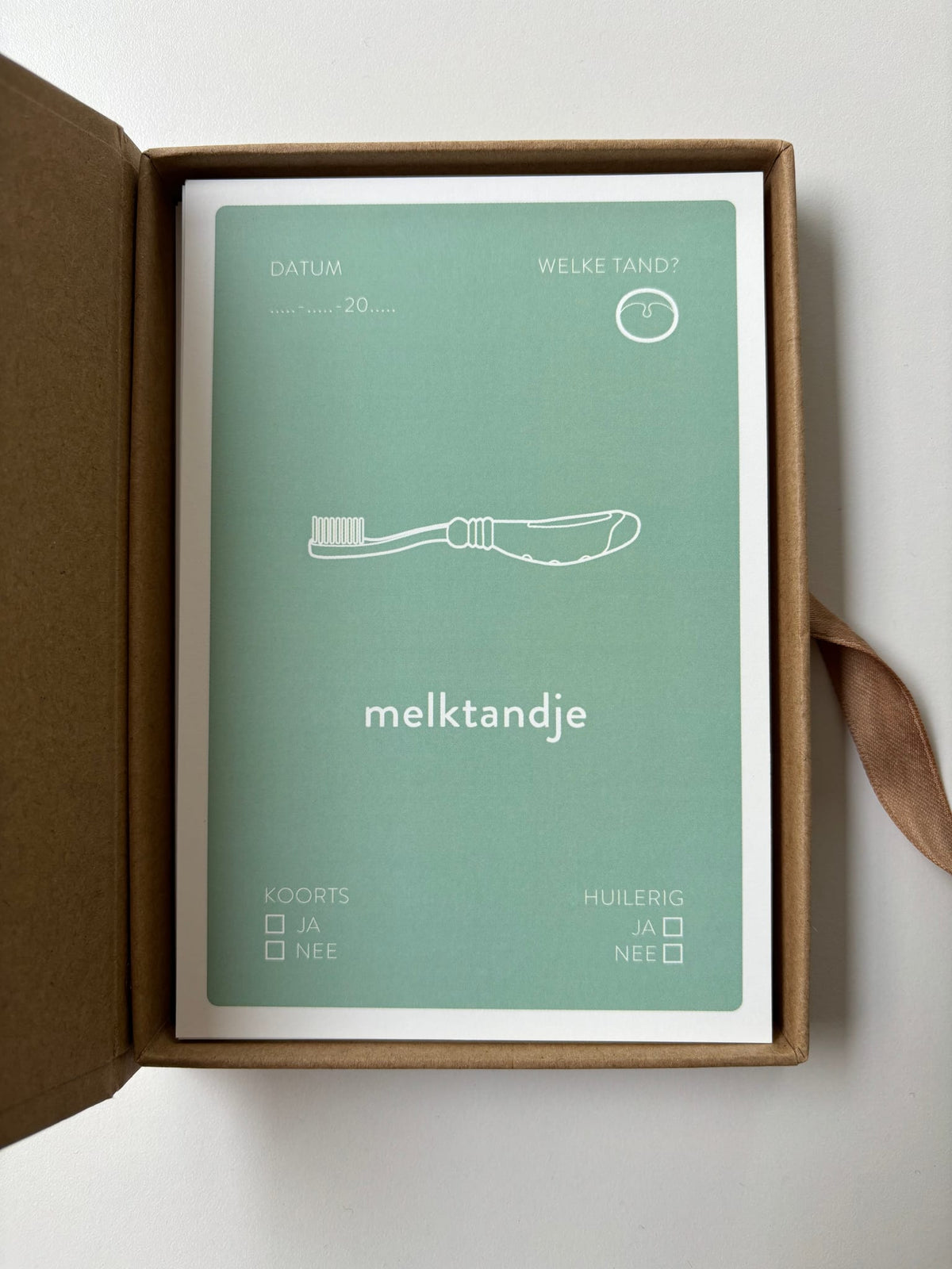 Geopend Baby Mail bewaardoosje met een mintgroene mijlpaalkaart ‘melktandje’ met een tandenborstel.