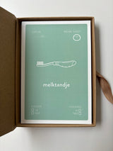 Geopend Baby Mail bewaardoosje met een mintgroene mijlpaalkaart ‘melktandje’ met een tandenborstel.