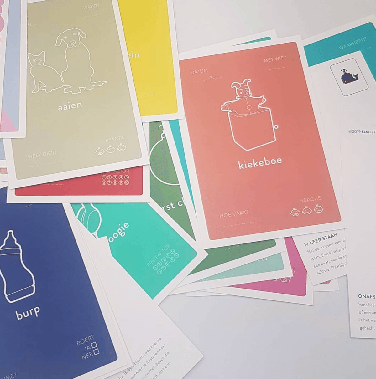Uitgespreide Baby Mail mijlpaalkaarten met onder meer ‘kiekeboe’, ‘aaien’ en ‘burp’.