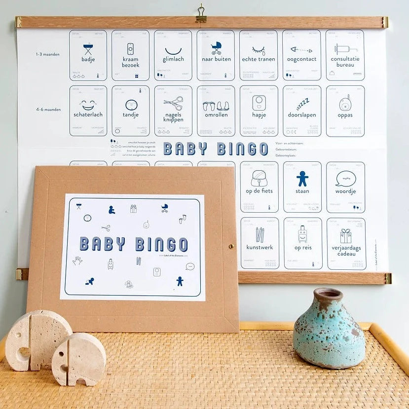 Baby Mijlpalen Bingo met blauwe pictogrammen aan houten ophanglatten, met de bruine enveloppe ervoor.