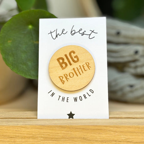 Houten Big Brother badge op een witte kaart met zwarte tekst en een ster, rechtop in een houten houder.