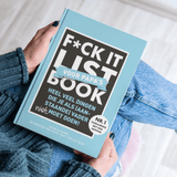 F*ck It List Book voor papa's met lichtblauwe cover, vastgehouden op schoot boven een spijkerbroek