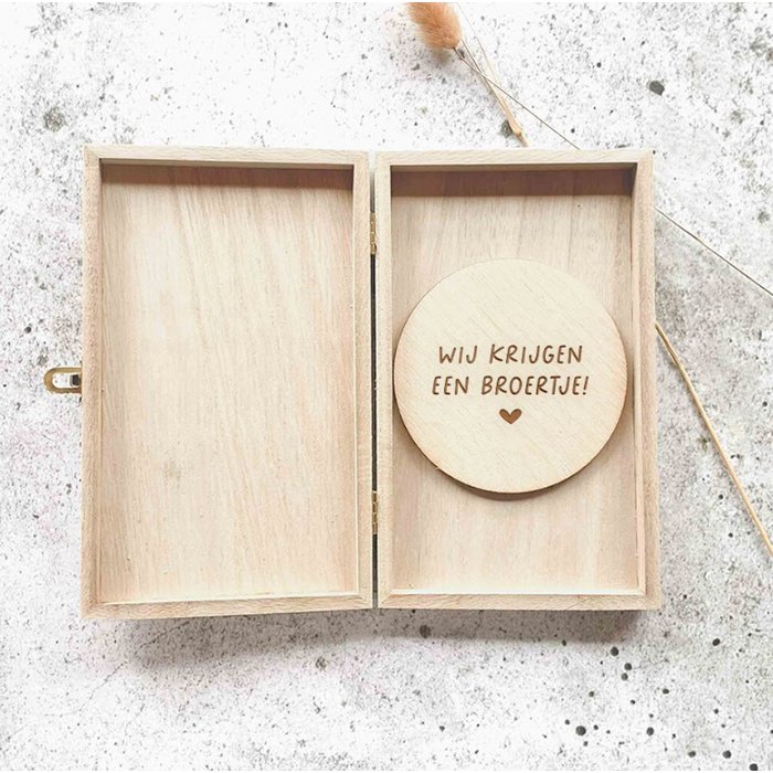 Open houten kistje met een ronde houten schijf met de tekst ‘Wij krijgen een broertje!’ en een hartje.