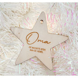 Houten kerstster met ‘Oma, de mooiste ster aan de hemel’ tussen witte, glanzende kerstslingers.