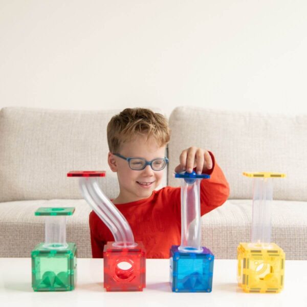 Kind met een bril speelt aan tafel met een Coblo knikkerbaan met groene, rode, blauwe en gele bouwblokken.