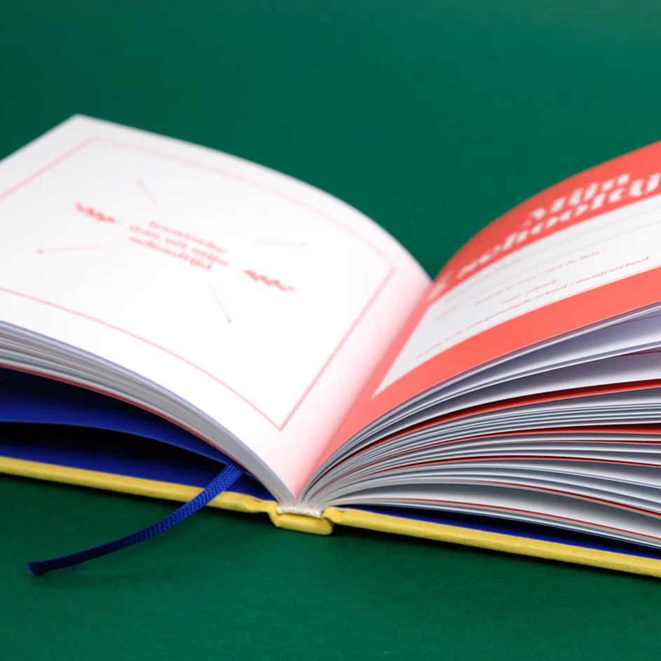 Mama Boekje van opzij, opengeslagen met witte en koraalrode pagina’s en een blauw leeslint