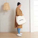 Vrouw met een ivoorkleurige Mom Bag Teddy Bouclé over haar schouder, gedragen bij een camelbruine jas.