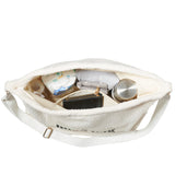 Open ivoorkleurige Mom Bag Teddy Bouclé met luiers, een fles, opgevouwen textiel en een portemonnee.