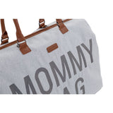 Detail van de grijze Mommy Bag verzorgingstas met bruine handvatten en grote donkere letters op de voorkant.