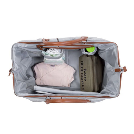 Open grijze Mommy Bag verzorgingstas van bovenaf, gevuld met luiers, babykleding en een opbergtasje.
