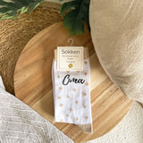 Witte sokken met beige stippen en het opschrift ‘Oma’, met productlabel op een ronde houten plank.