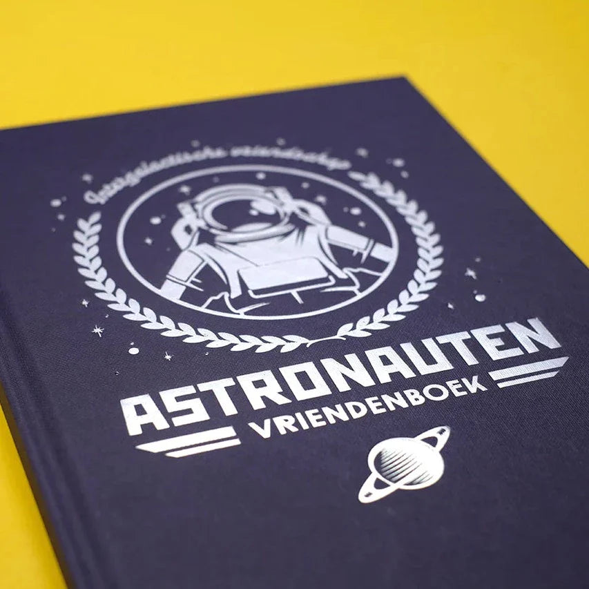Detail van de donkerblauwe kaft van het astronautenvriendenboek met witte astronaut, sterren en planeet.