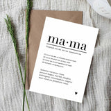 Witte A6-ansichtkaart met zwarte tekst over mama en een hartje, op een bruine envelop naast groene takjes.