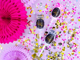 Drie Confetti Push Pops tussen roze, gouden en zilveren confetti en roze en lila papieren waaiers.