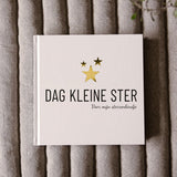 Invulboek Dag Kleine Ster op grijze stof, met lichte kaft, drie gouden sterren en de tekst ‘Voor mijn sterrenkindje’.