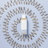 Fles Naïf Milky Badolie omringd door zonnebloempitten in cirkels op een lichtblauwe achtergrond