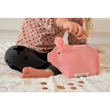 Kind houdt een munt boven het roze Piggy-spaarvarken, met losse munten op het bed