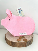 Roze Piggy-spaarvarken met een biljet van 20 euro en munten op een houten schijf