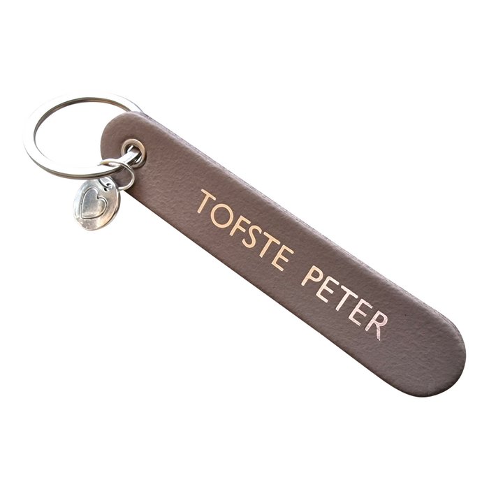 Taupe sleutelhanger met opdruk 'Tofste peter', zilverkleurige sleutelring en hartbedel.