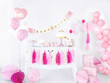 Baby Girl-slinger boven een witte kast met taart en gebakjes, omringd door roze en witte feestdecoratie.