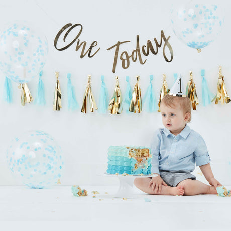 Blauwe cake smash kit met ballonnen en gouden 'One Today'-slinger bij een kind met een blauwe verjaardagstaart.